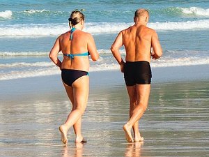 Salud Ecológica: Hombre y mujer corriendo por la playa para envejecer con salud